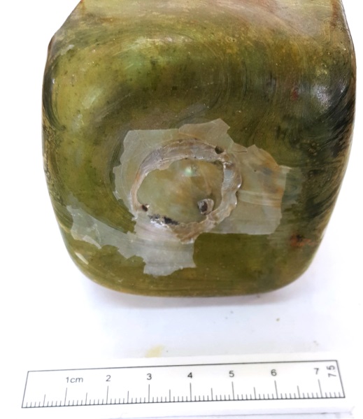 Base of bottle with pontil mark inside, and scale rule in front.