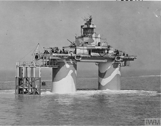 Contemporary B&W photograph of twin-legged sea fort painted in dazzle camouflage