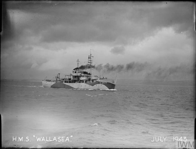 Historic B&W photograph of ship seen in profile with painted blocks of colour breaking up the hull profile. A large plume of black steam issues from her funnel, as she makes her way under heavy clouds in the sky.
