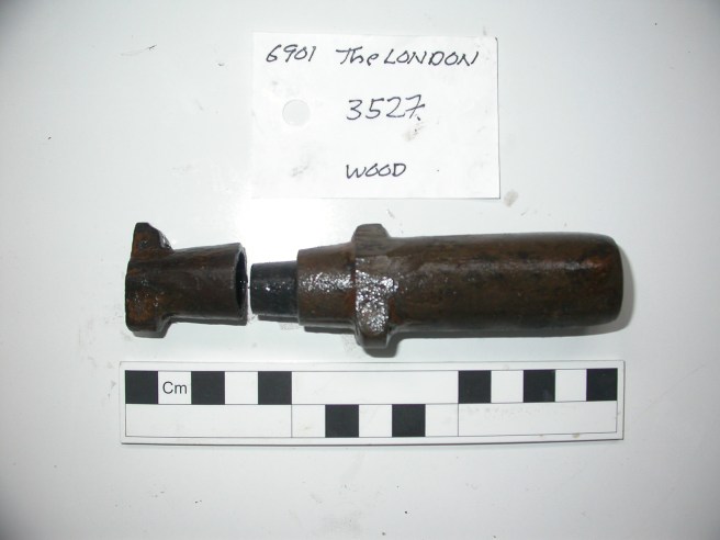 At top of image, label naming the artefact with text '6901: The London 3527: wood'. Centre of image, wooden bottle, with stopper to left, body of bottle to right, underneath this is a scale marked off in centimetres.