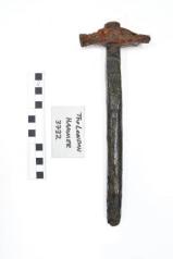 Hammer laid vertically showing head with concretion removed, scale rule and label to left