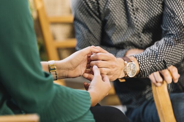Hands of an elderly man being held by a social worker