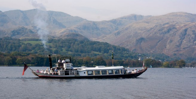 Modern colour photo of the Gondola on the lake against a background of green tree and heather-covered mountains