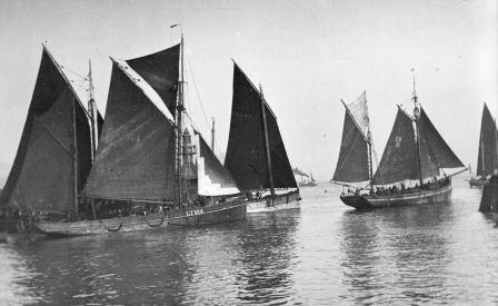 Black and white photographs of several Lowestoft smacks under full sail.
