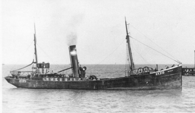Black and white photo of steam trawler, with steam coming out of its funnel.