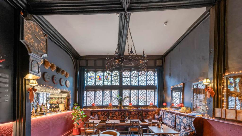 The interior of a historic public house showing timber construction and a window with heraldic decoration.