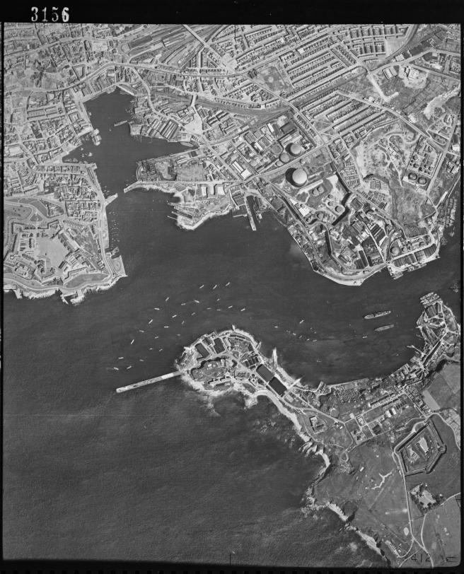 Historic B&W aerial photograph of Plymouth showing the Cattewater and Plymouth Sound with some vessels moored off Mount Batten to the lower half of the image, and to the upper half a built-up cityscape. 