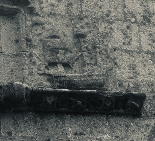 Modern black & white photo of a stone ledge on a wall with a carved relief of a sailing ship.