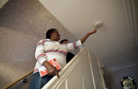 A person in their home testing their smoke alarm to check it works.