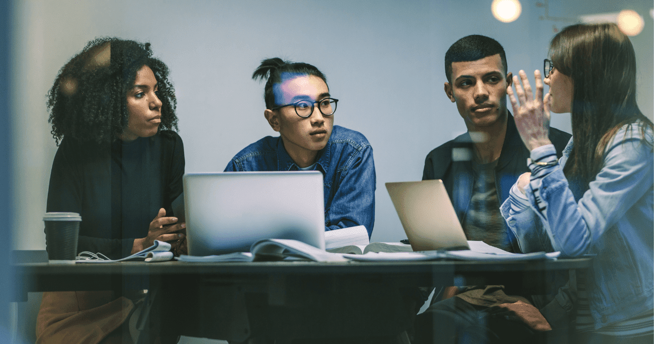 Four People At A Table Learning Together With Laptops