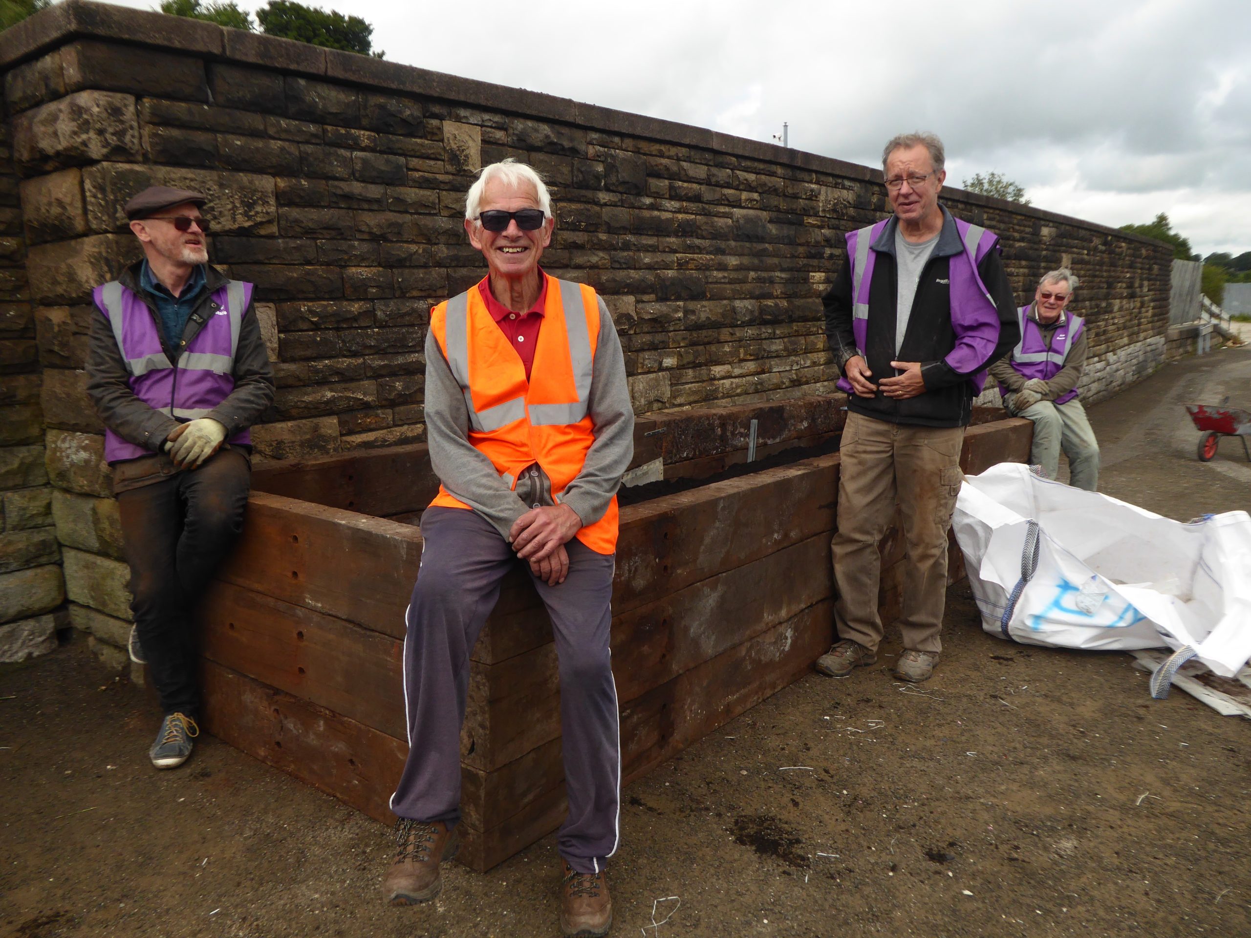 four volunteers smiling at the cameraposing around a garden planter