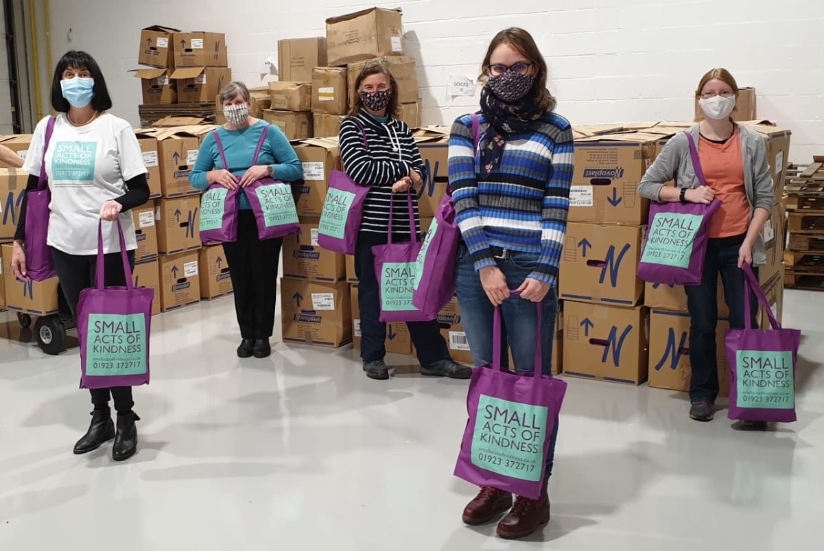 People standing apart holding small acts of kindness bags