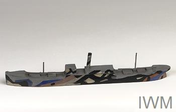 3D ship model painted in colour with abstract black patterns, photographed against a grey background.