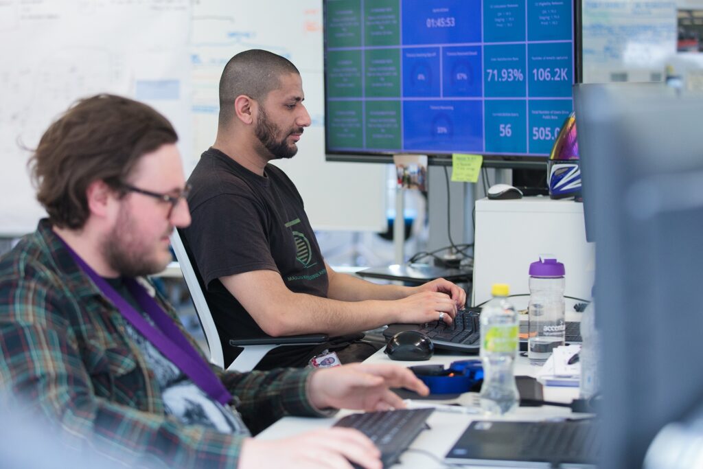 Two casually dressed males sitting at computers working