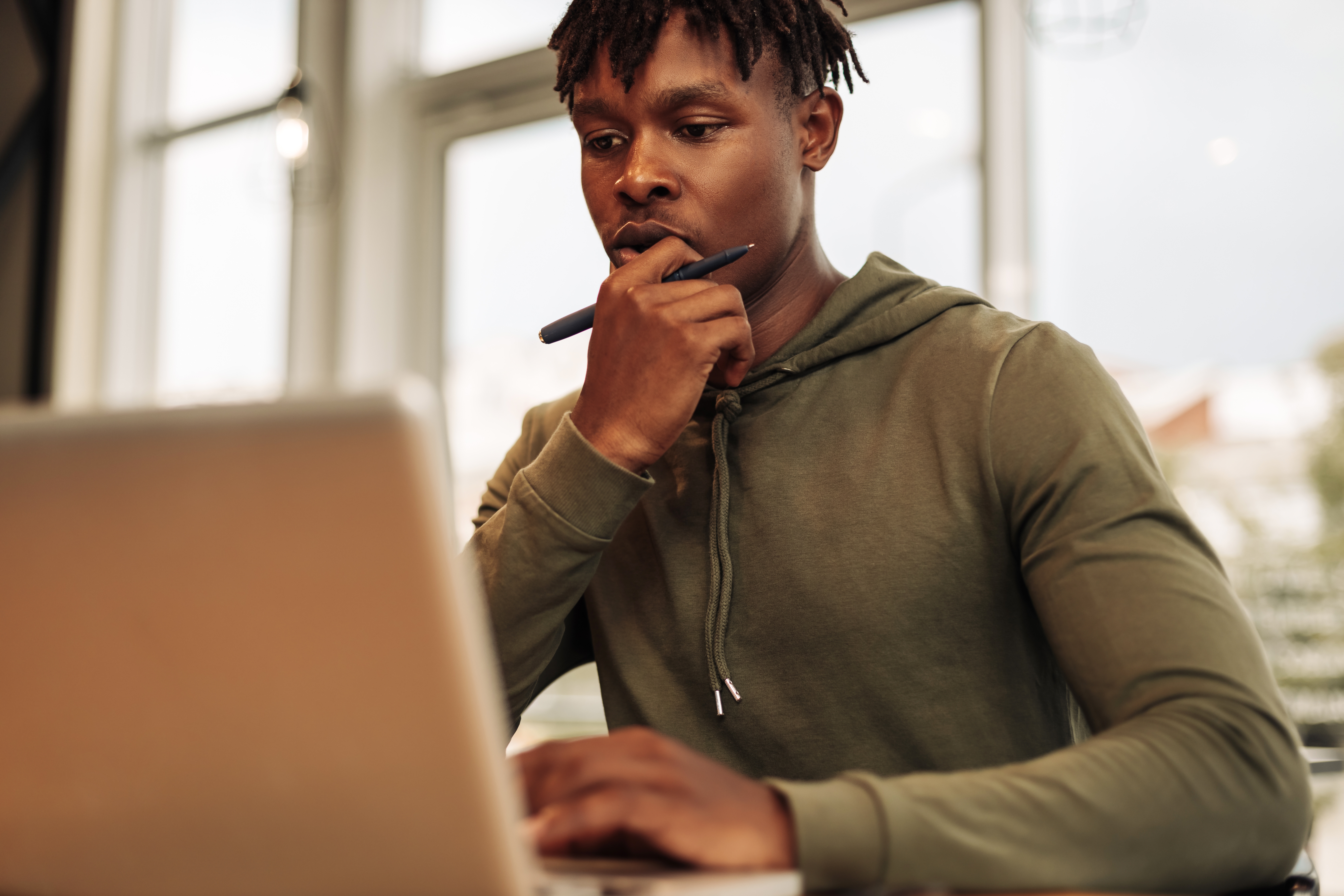 Thoughtful young man working on a laptop.