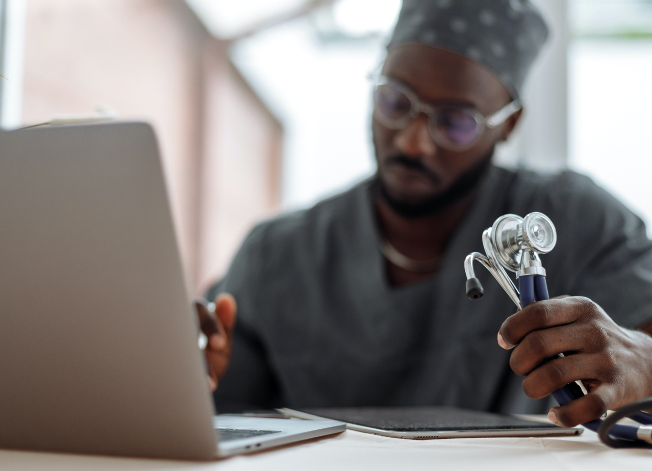 Doctor working in front of laptop holding stethoscope