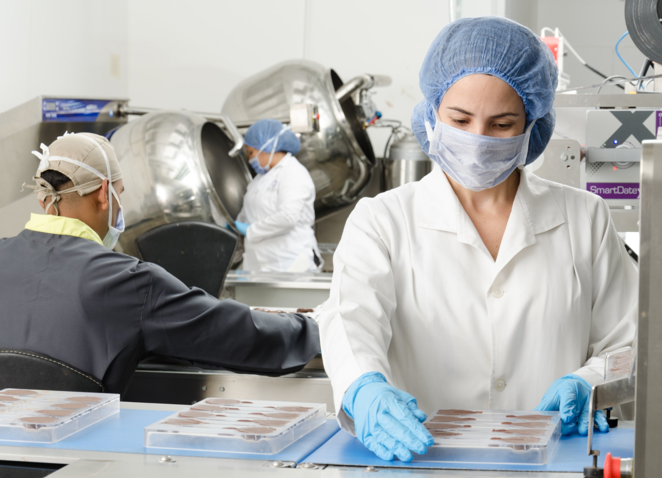 Woman in face mask, hair net and gloves working in a sterile environment