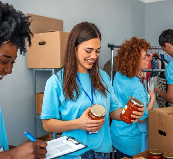 Two women smiling while working for a charity with two more people in the background