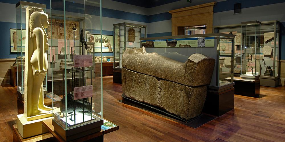 Internal view of a museum gallery showing objects including Egyptian sculptures and artwork.