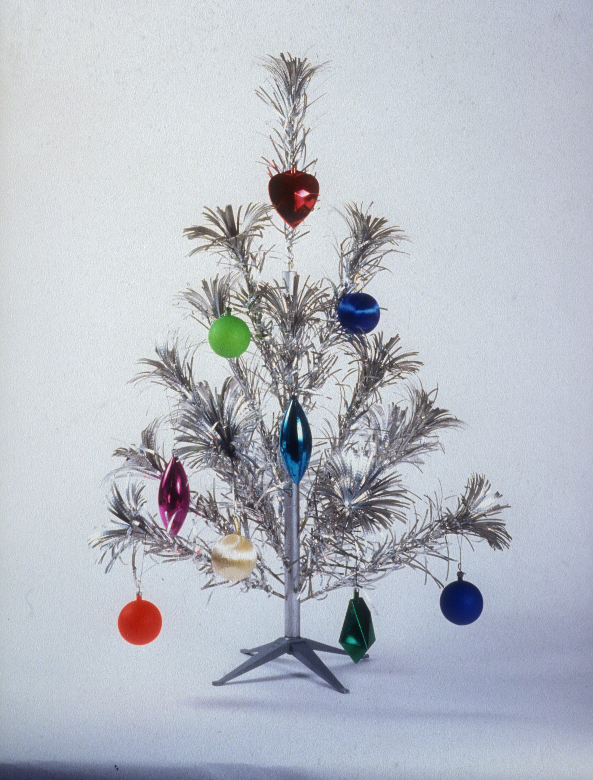 Silver aluminum Christmas tree with colorful glass ball ornaments and plastic base
