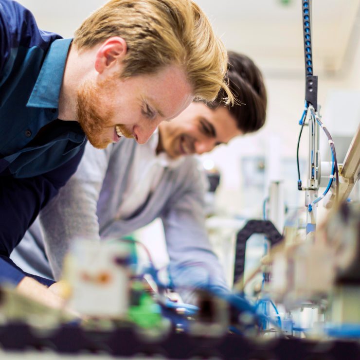 Two young handsome engineers working on electronics components and fixing broken chips Two Young Handsome Engineers Working On Electronics Components