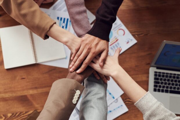 multiple people placing their hands on top of each other in a circle