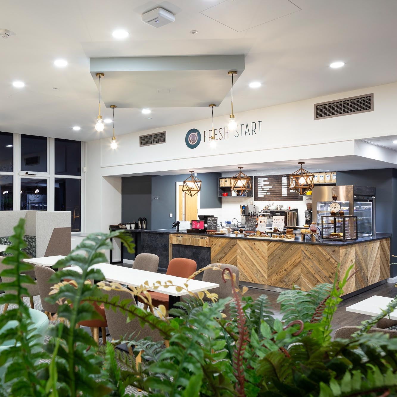 Fresh Start Coffee Shop at Newport site with comfortable seating, tables and foliage in the foreground.