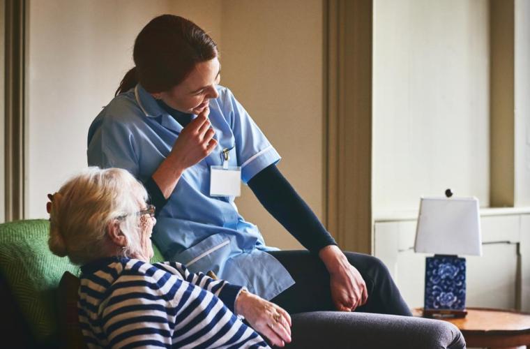 Nurse and elderly woman spending good time at care home 
