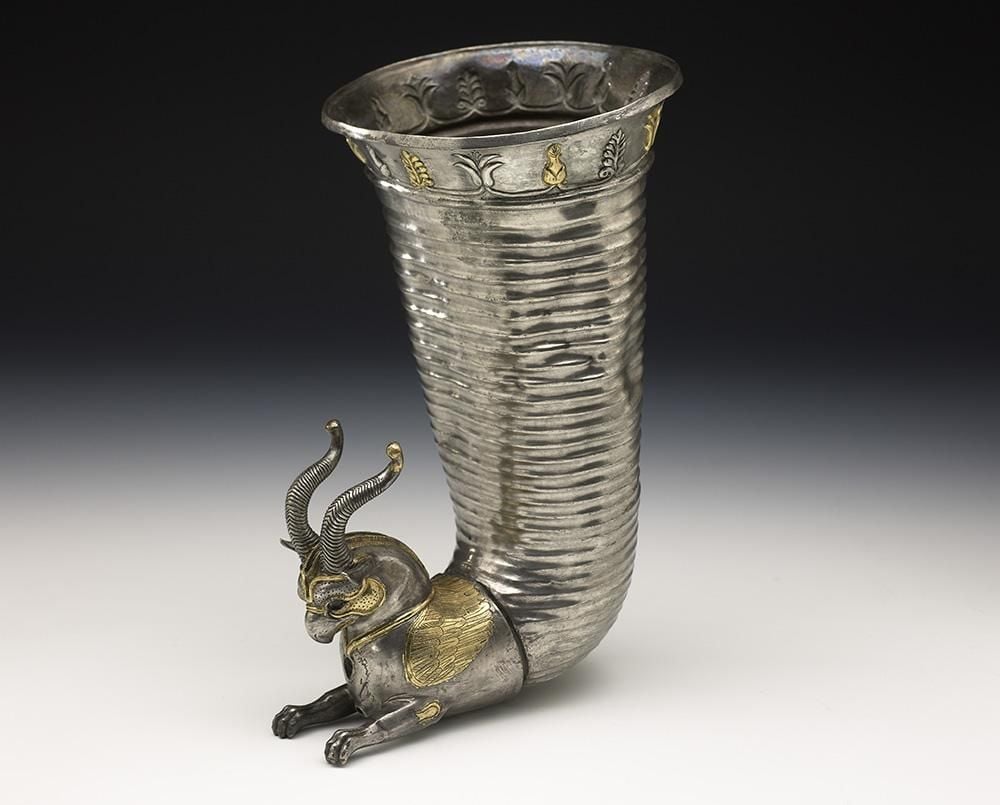 A ribbed silver horn with the torso and head of a griffin attached at the bottom.