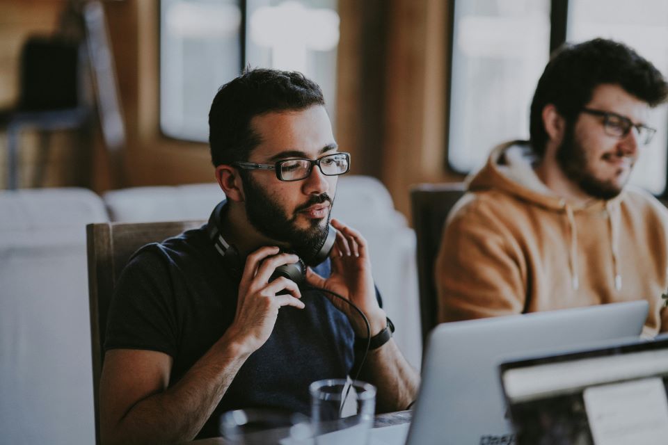 Two men sitting in front of computers.