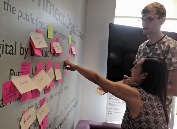 A woman pointing at a wall with Post-It notes on it