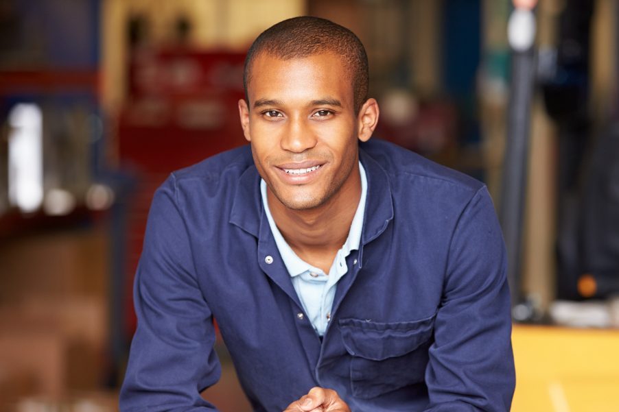 Smiling Man Sitting At A Table In A Warehouse