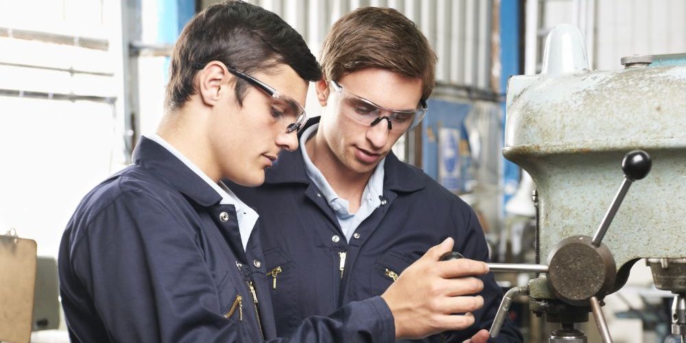 Two Men Working On A Machine In A Factory