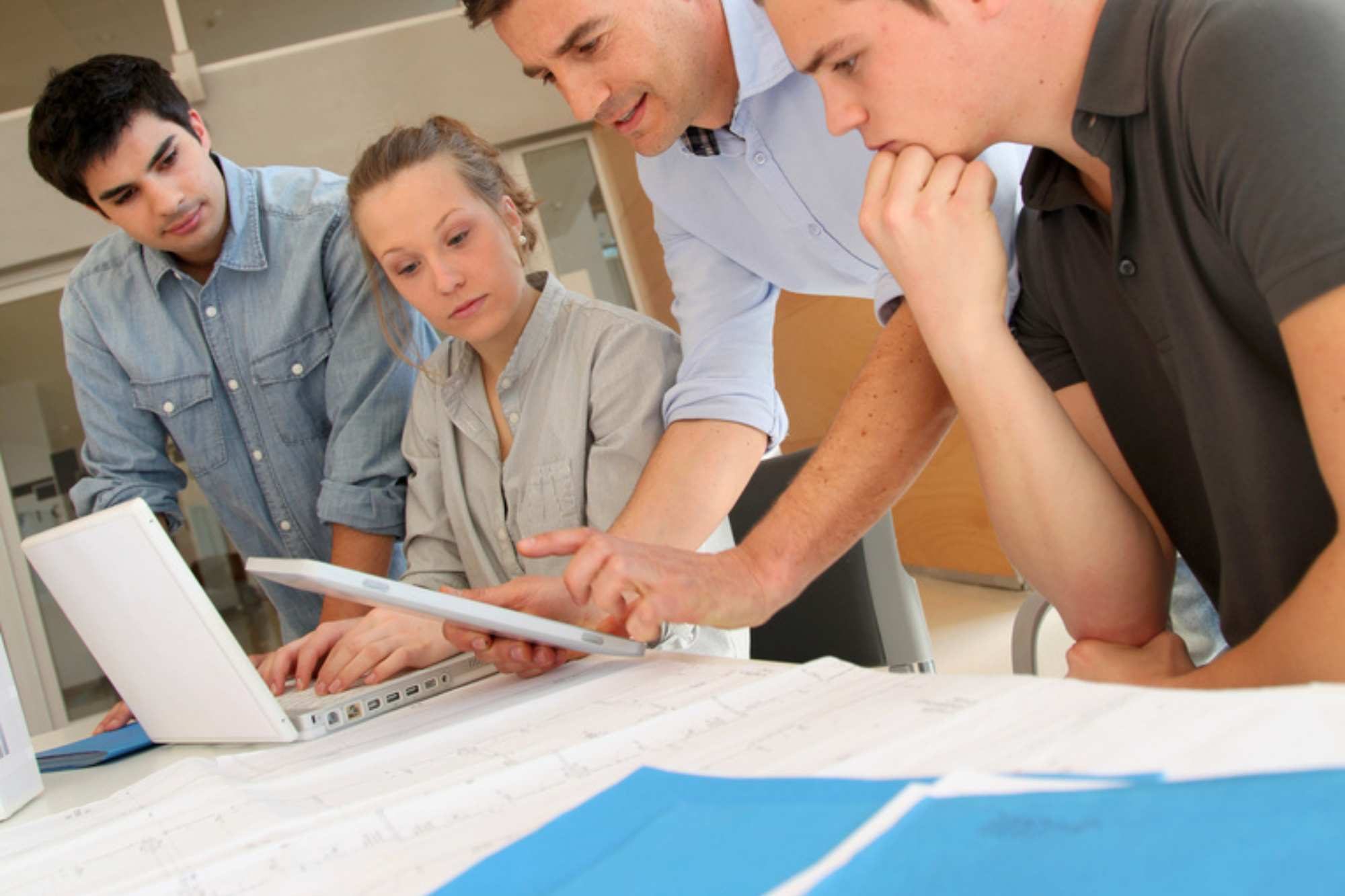 Group Of Learners Looking At Blue Print Plans