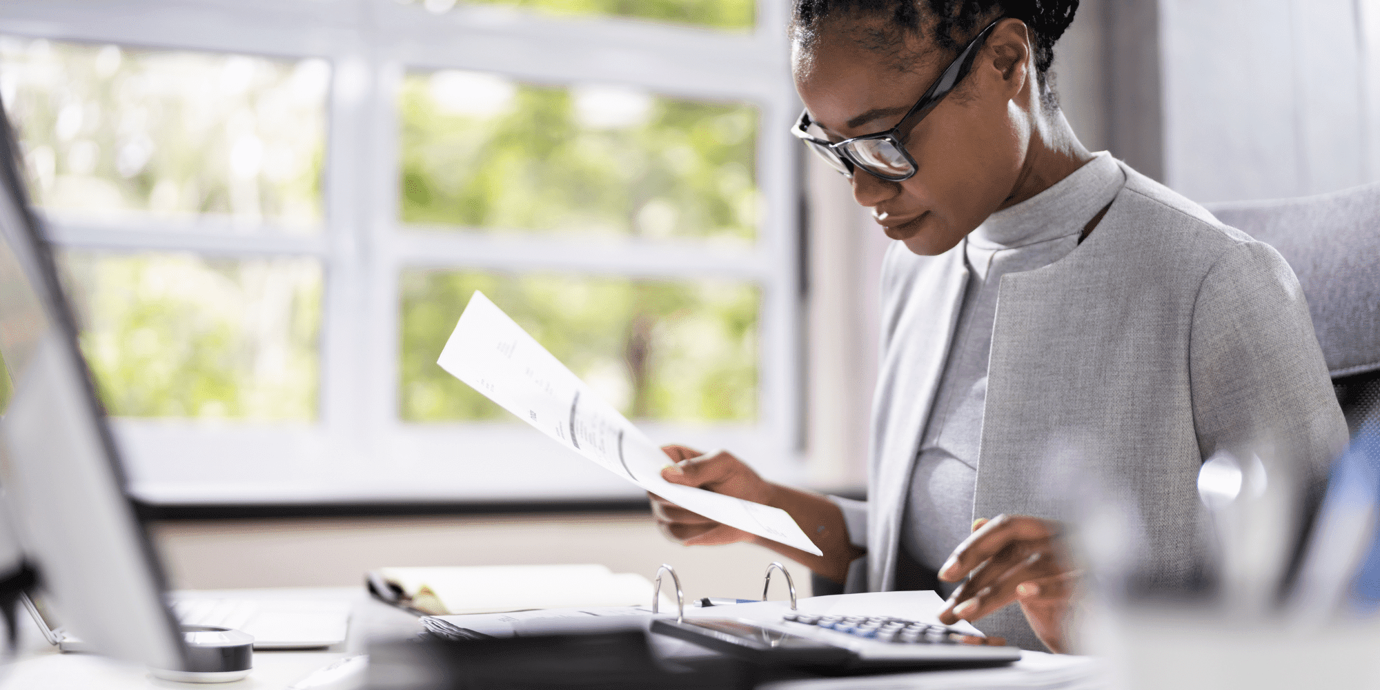Project Control Lady In Glasses At A Computer With Papers And A Calculator