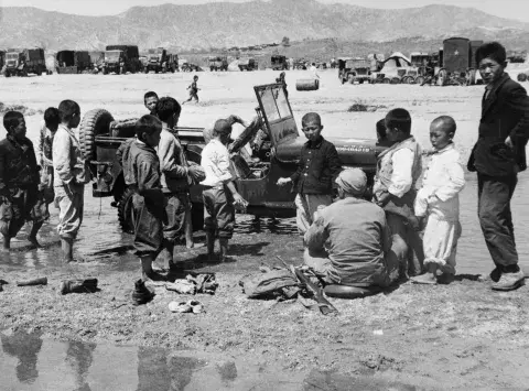 Korean children help to wash down American Jeep.