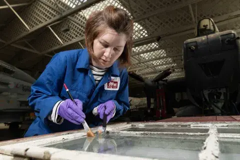 A female conservator working on an object, holding her tools