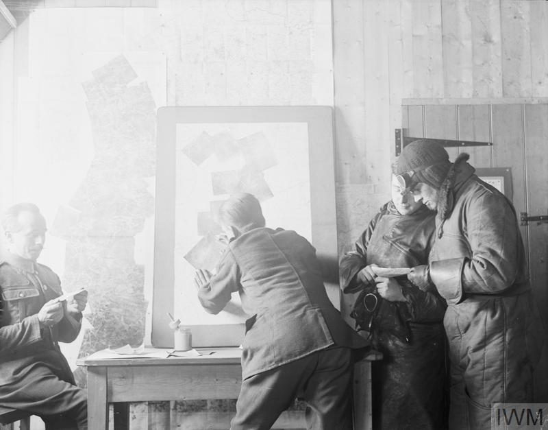 Four men stand in front of a board featuring overlapping photographs. The men are studying the images