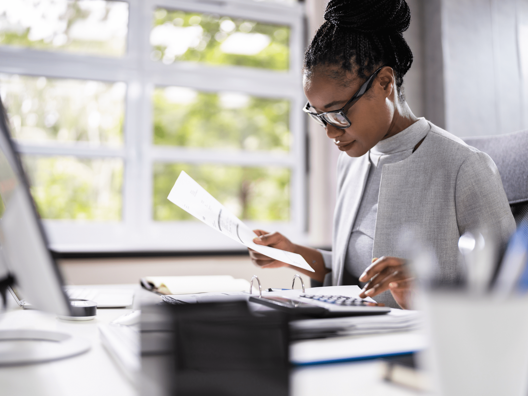 Project Control Lady In Glasses At A Computer With Papers And A Calculator