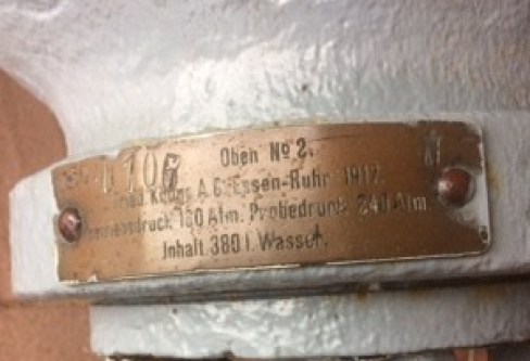 Detail of metal plate on neck of white air cylinder, engraved in German.