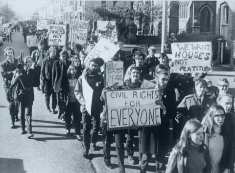 Students at Belfast University, carrying banners proclaiming 'Civil rights for everyone', the 'Special Powers Act Must Go', and 'We want Houses Not Platitudes', march through Belfast to the City Hall in October 1968.