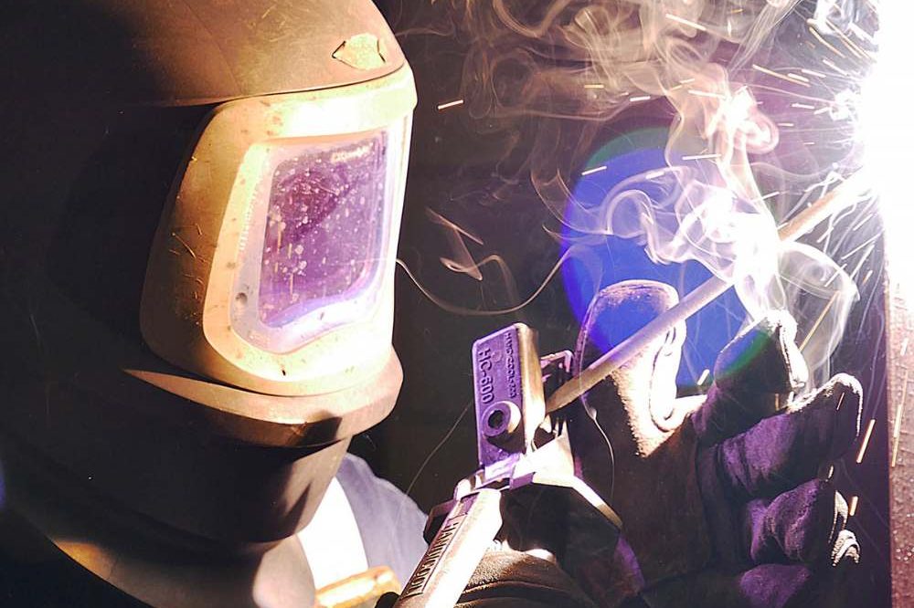 Person Welding In A Metal Helmet