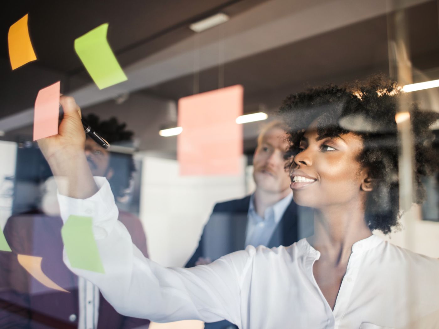 Project Management training - Woman Writing On Post It Note In Office