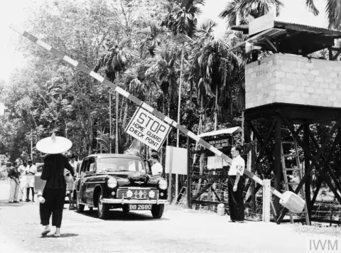 A member of the Malayan Home Guard mans a check point on the edge of a town.
