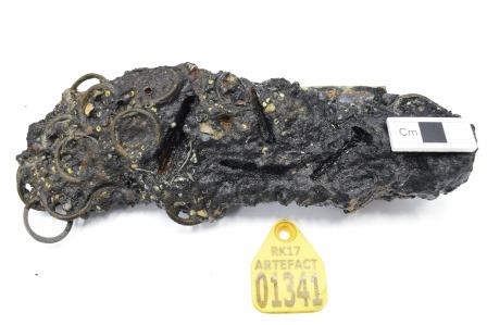 Detail of obverse side of concretion, with rings visible on the left: scale rule on object on the right, yellow tag below