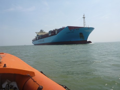 A huge container ship dwarfs the dive vessel as it passes close by.