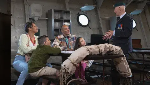 Family listening to a war veteran onboard HMS Belfast