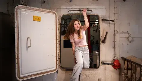 Girl entering though a hatch onboard HMS Belfast
