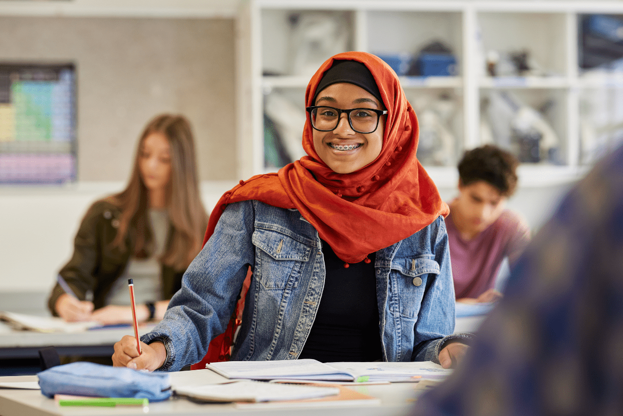 Smiling student girl in glasses working at a desk