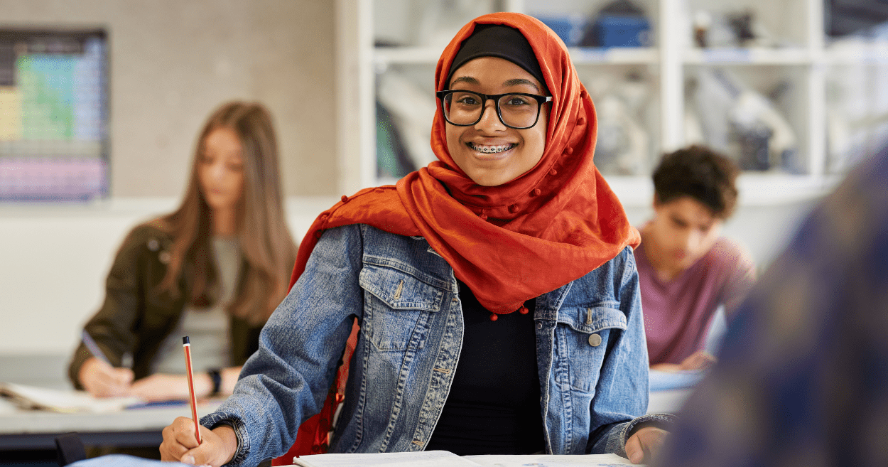 Smiling student girl in glasses working at a desk